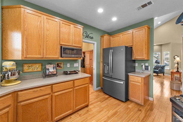 kitchen featuring built in microwave, light countertops, visible vents, light wood-style floors, and stainless steel fridge