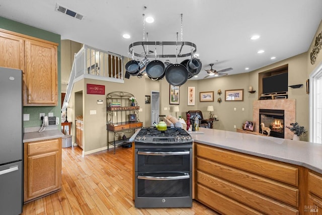 kitchen with stainless steel appliances, visible vents, light wood-type flooring, open floor plan, and ceiling fan