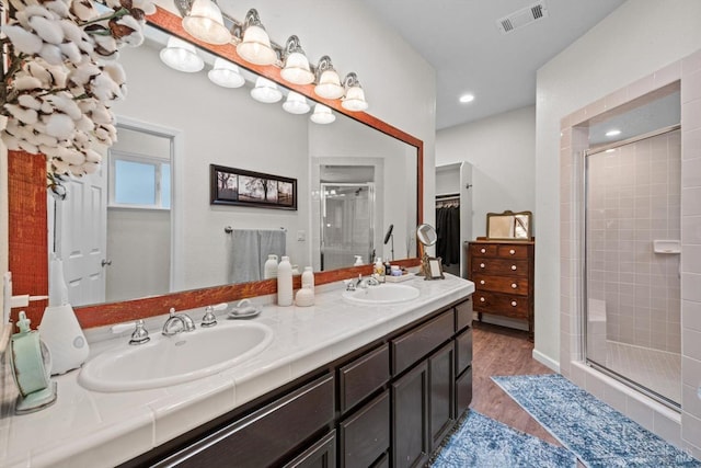 full bathroom featuring wood finished floors, visible vents, a stall shower, and a sink