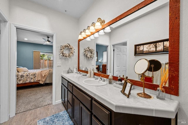 bathroom featuring double vanity, wood finished floors, a ceiling fan, connected bathroom, and a sink