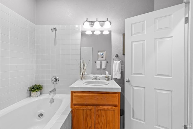 full bath featuring a textured wall and vanity