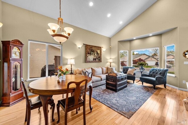 living area featuring high vaulted ceiling, baseboards, and light wood-type flooring