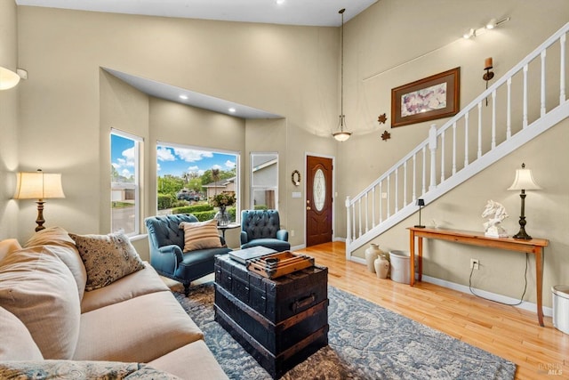 living area with stairway, wood finished floors, baseboards, a high ceiling, and recessed lighting