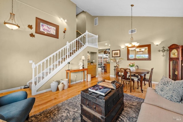 living area featuring high vaulted ceiling, wood finished floors, stairs, and visible vents