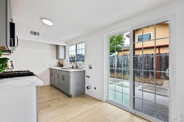 240 Rinaldo Dr, Vallejo, CA 94589 - kitchen featuring a sink, gray cabinets, light wood-style flooring, lofted ceiling, and visible vents
