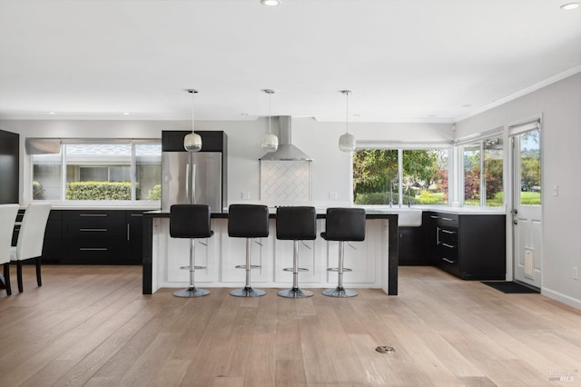 331 Laurel Leaf Pl, Santa Rosa, CA 95409 - kitchen featuring freestanding refrigerator, a kitchen bar, wall chimney exhaust hood, and dark cabinets