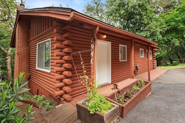 view of home's exterior featuring a chimney, a garden, and log siding
