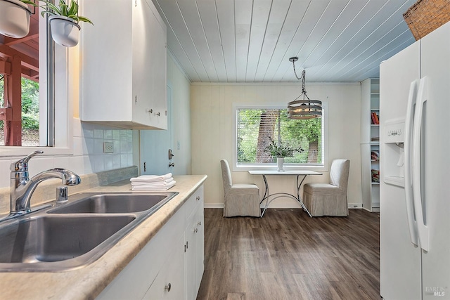 kitchen featuring white refrigerator with ice dispenser, a sink, white cabinets, and plenty of natural light