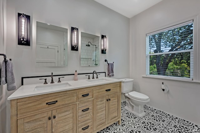 full bath featuring a tile shower, a sink, double vanity, and toilet
