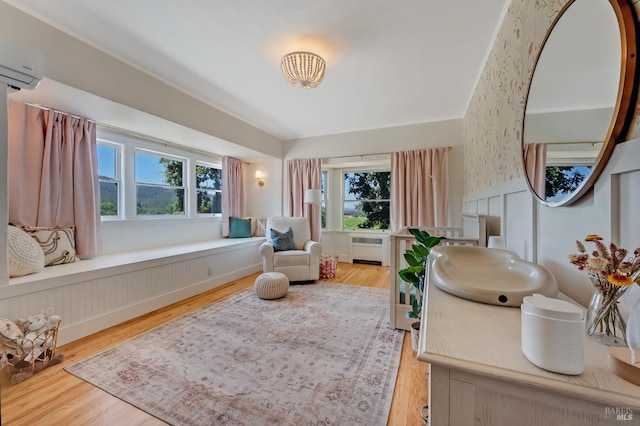 sitting room with radiator, a wall mounted AC, and wood finished floors