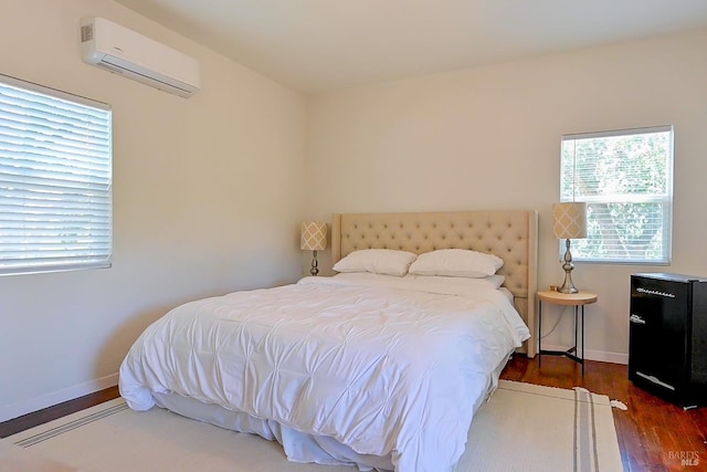 bedroom with baseboards, wood finished floors, and a wall mounted AC