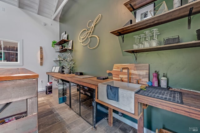 office area featuring lofted ceiling with beams, beverage cooler, wood finished floors, and a sink