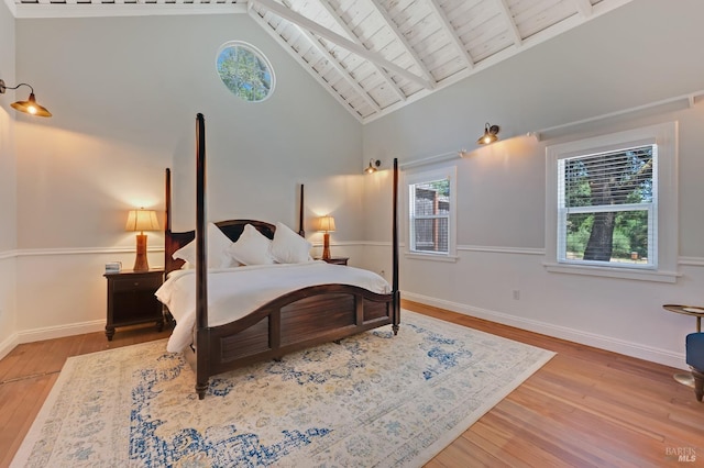 bedroom featuring beamed ceiling, hardwood / wood-style flooring, baseboards, and high vaulted ceiling
