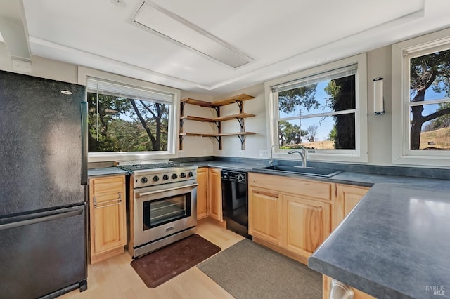 kitchen featuring dark countertops, light brown cabinets, a sink, and black appliances