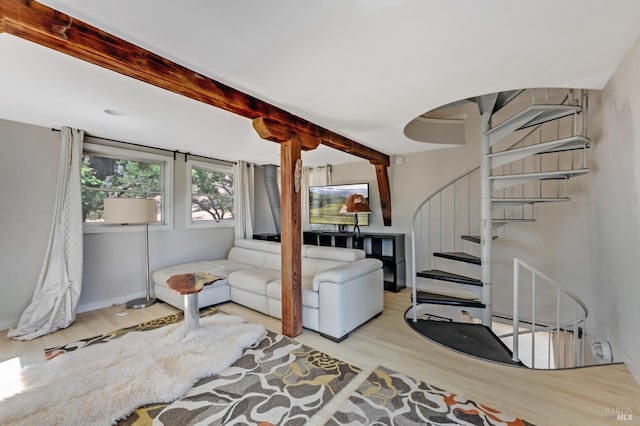 living room featuring wood finished floors, beam ceiling, and stairs