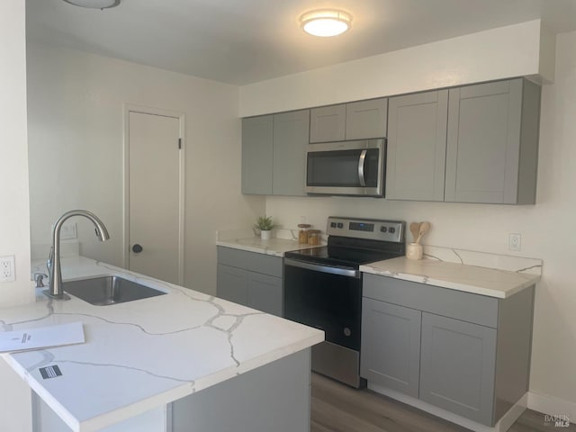 106 Oliva Ct Unit C, Novato, CA 94947 - kitchen featuring dark wood-style floors, light stone counters, stainless steel appliances, a sink, and gray cabinetry