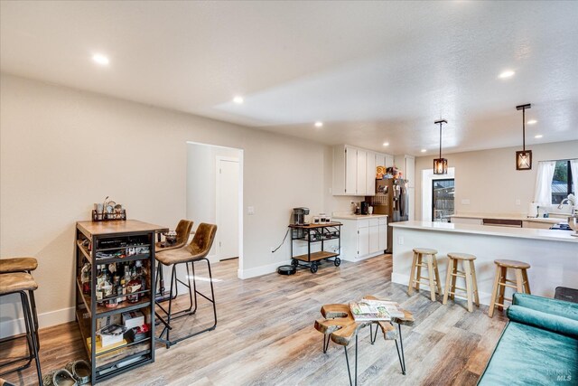 living area featuring baseboards, recessed lighting, and light wood-style floors