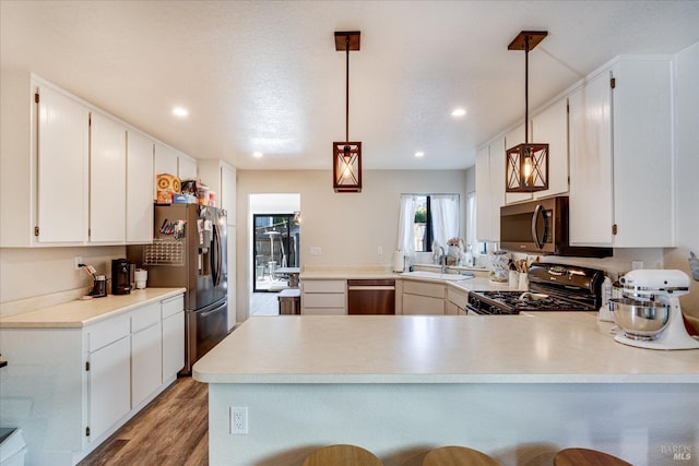 kitchen with a peninsula, a sink, light wood-type flooring, recessed lighting, and appliances with stainless steel finishes