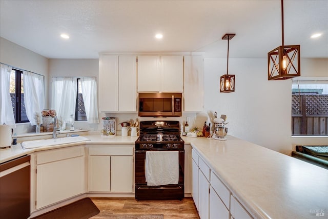 kitchen with black range with gas stovetop, dishwasher, a sink, stainless steel microwave, and a wealth of natural light