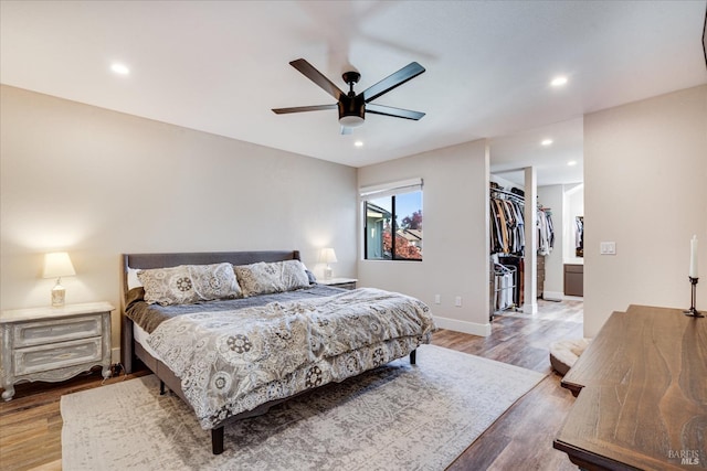 bedroom with wood finished floors, a spacious closet, recessed lighting, and ceiling fan