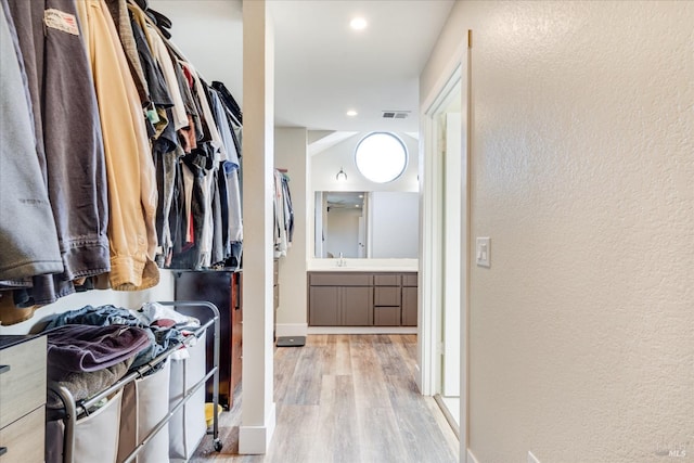 walk in closet featuring visible vents, light wood finished floors, and a sink