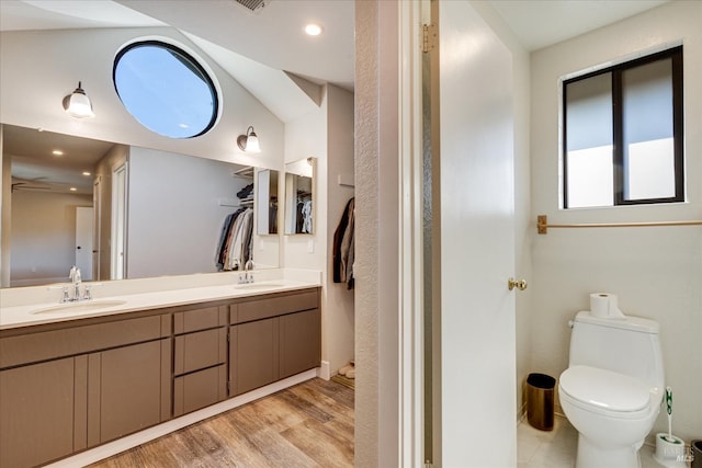 bathroom with toilet, wood finished floors, a sink, and double vanity