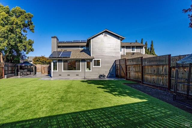 back of house with a fenced backyard, solar panels, a gazebo, and a patio