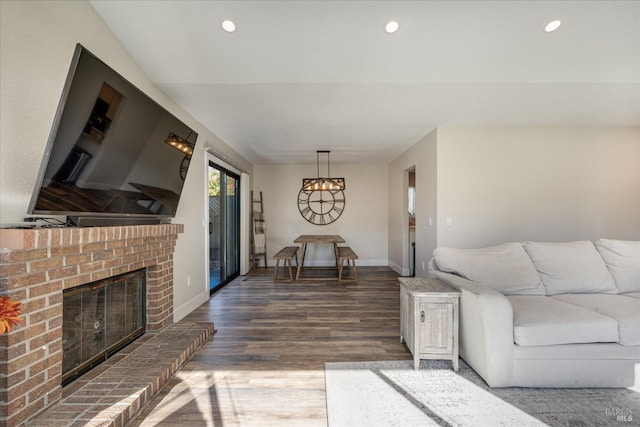 living room featuring baseboards, a brick fireplace, wood finished floors, and recessed lighting