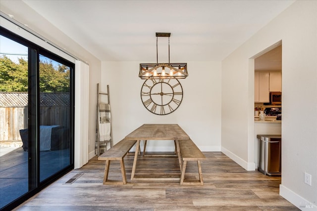 unfurnished dining area with baseboards, wood finished floors, and a chandelier