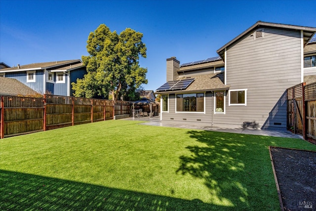 back of house with a fenced backyard, solar panels, a yard, and a patio