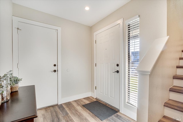 foyer featuring baseboards, wood finished floors, stairs, and recessed lighting