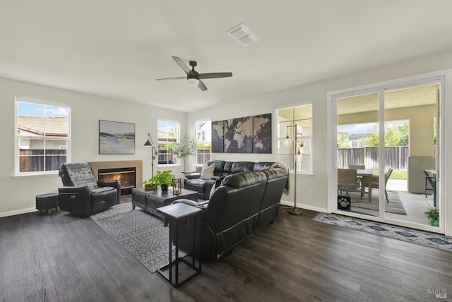 living room featuring baseboards, a ceiling fan, visible vents, and dark wood finished floors