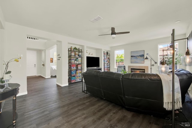 living room featuring a ceiling fan, visible vents, and dark wood-style flooring