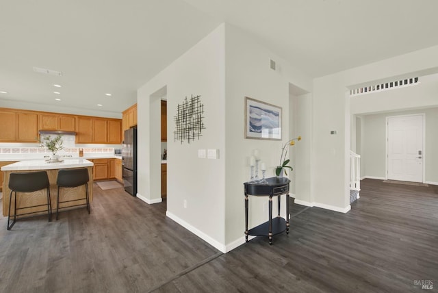 kitchen with dark wood-style flooring, visible vents, baseboards, freestanding refrigerator, and light countertops