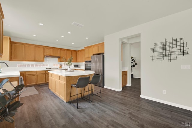 kitchen featuring under cabinet range hood, light countertops, visible vents, a kitchen island, and appliances with stainless steel finishes
