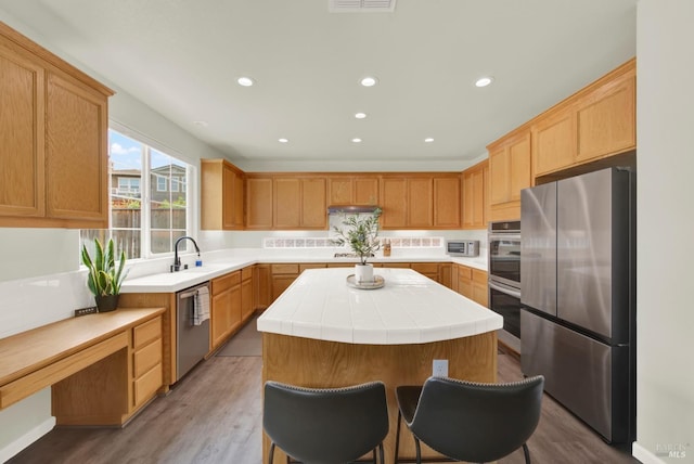 kitchen with light wood-style floors, a kitchen island, appliances with stainless steel finishes, and a sink