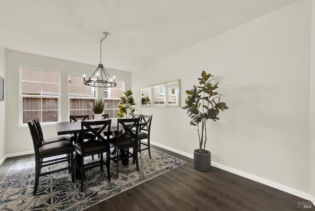 dining space featuring dark wood finished floors, baseboards, and a notable chandelier