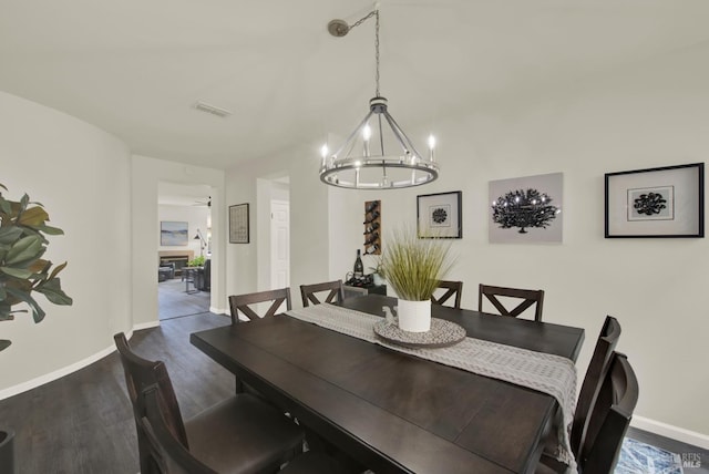 dining area with dark wood finished floors, visible vents, baseboards, and a notable chandelier
