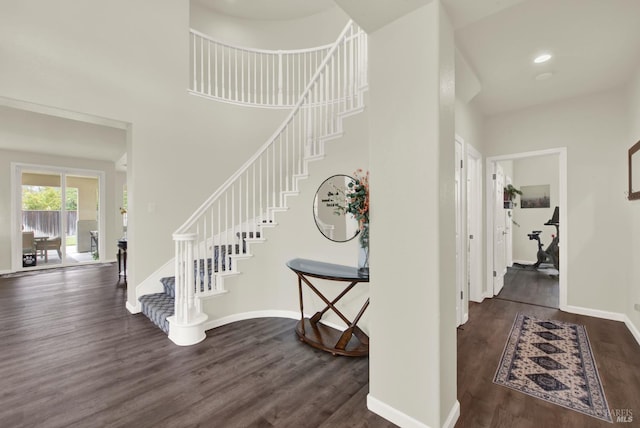 entrance foyer featuring a towering ceiling, baseboards, stairs, and dark wood-style flooring