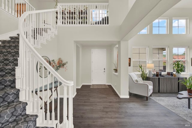 entryway with baseboards, wood finished floors, a towering ceiling, and stairs