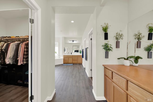 hallway with baseboards, wood finished floors, and recessed lighting