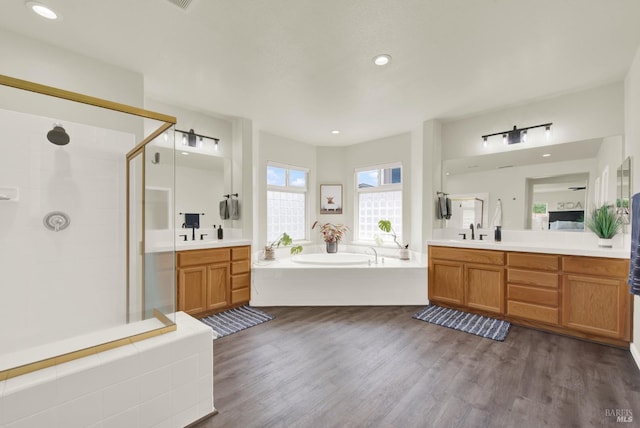 bathroom with a garden tub, wood finished floors, and a stall shower