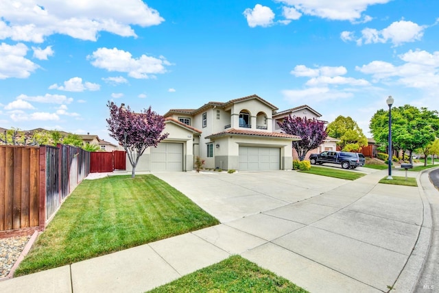 mediterranean / spanish-style house featuring a tile roof, a front lawn, concrete driveway, fence, and stucco siding
