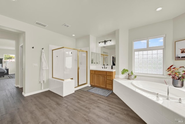 bathroom featuring a shower stall, wood finished floors, visible vents, and a garden tub