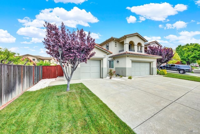 mediterranean / spanish home with concrete driveway, a front lawn, a tiled roof, fence, and stucco siding