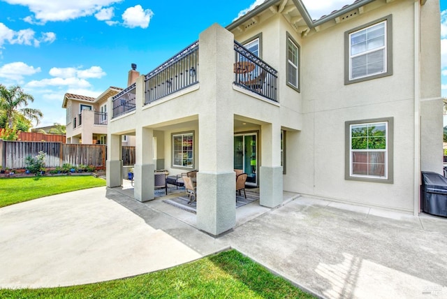 back of property with stucco siding, fence, a balcony, and an outdoor hangout area