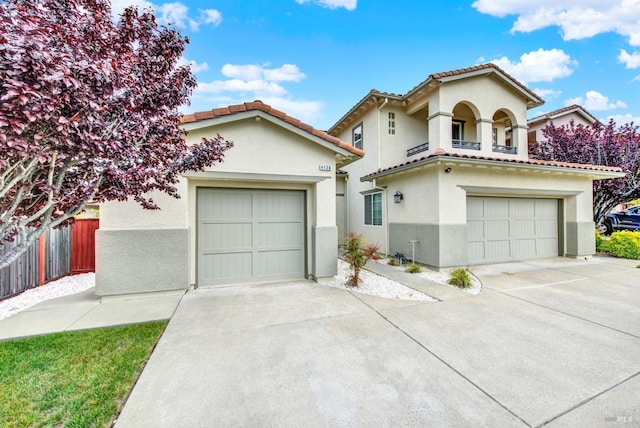 mediterranean / spanish-style home featuring stucco siding, a tiled roof, fence, and concrete driveway