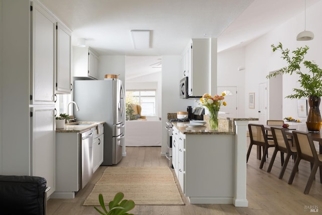 kitchen featuring light wood-style floors, white cabinetry, stainless steel appliances, and dark stone countertops