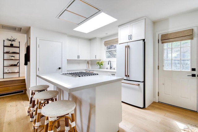 11 Cedar St, San Anselmo, CA 94960 - kitchen with light wood finished floors, white cabinetry, stainless steel gas stovetop, light countertops, and high end white refrigerator
