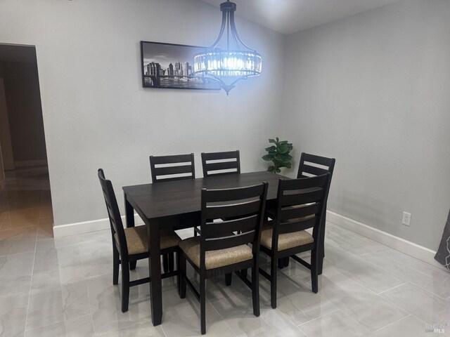 dining space featuring baseboards and a notable chandelier